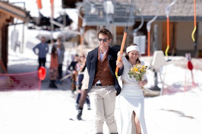 Miniature Location salle La Clusaz (Haute-Savoie) - Le 1647 #3 Un couple en tenue de mariage se tient dans un paysage montagneux au coucher du soleil, entouré de sapins.