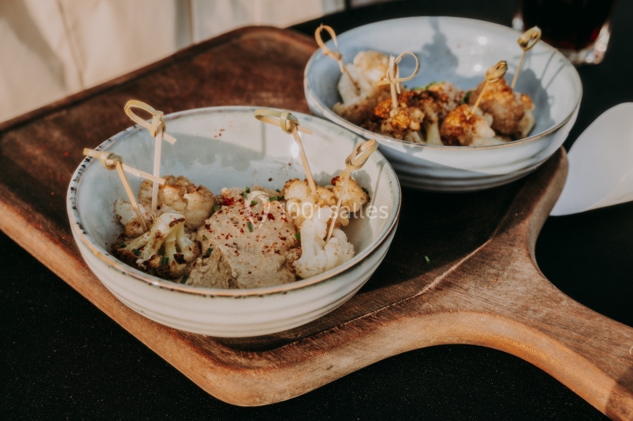 Deux bols en céramique contenant des brochettes de chou-fleur grillé, posés sur une planche en bois.