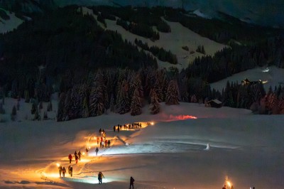 Un DJ mixe sur son ordinateur portable lors d'une soirée animée dans un espace intérieur éclairé par des lumières colorées.