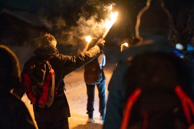 Un DJ mixe sur son ordinateur portable lors d'une soirée animée dans un espace intérieur éclairé par des lumières colorées.