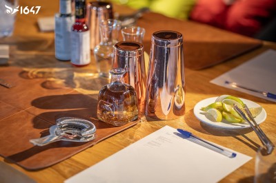 Un DJ mixe sur son ordinateur portable lors d'une soirée animée dans un espace intérieur éclairé par des lumières colorées.