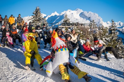 Un DJ mixe sur son ordinateur portable lors d'une soirée animée dans un espace intérieur éclairé par des lumières colorées.