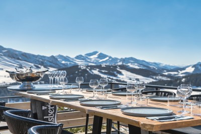 Un DJ mixe sur son ordinateur portable lors d'une soirée animée dans un espace intérieur éclairé par des lumières colorées.