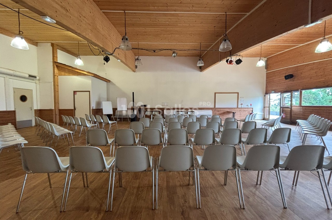 Salle de réunion avec des rangées de chaises blanches vides, un tableau blanc et un plafond en bois.