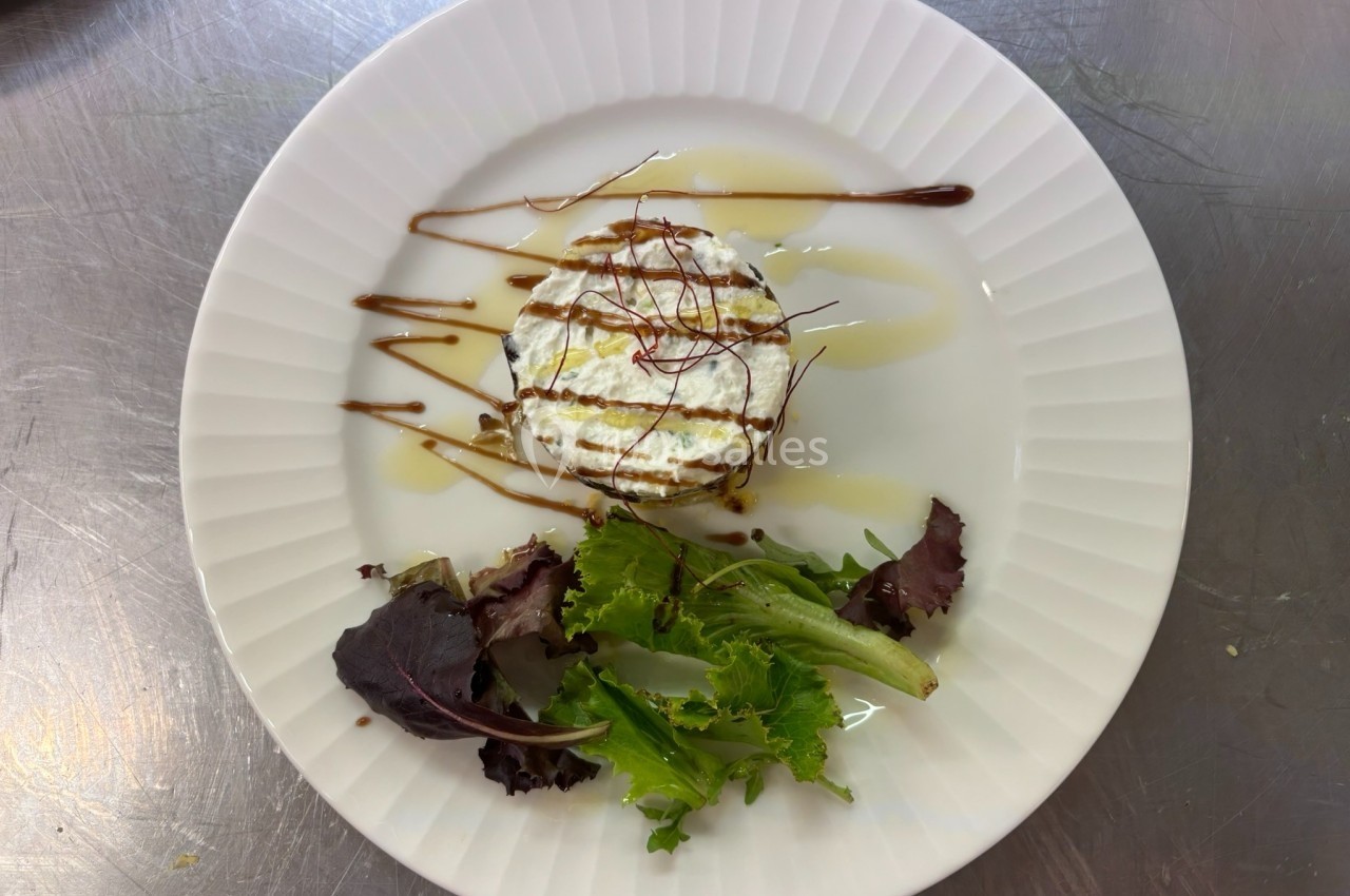 Assiette contenant un fromage frais garni de sauce, accompagné de jeunes pousses de salade.