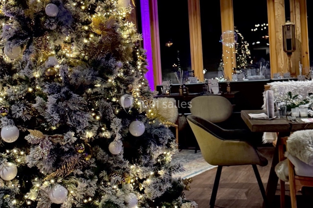 Sapin de Noël décoré avec guirlandes lumineuses et boules, entouré de cadeaux, dans une salle à manger chaleureuse.