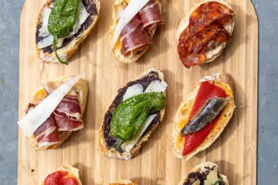 Tentacules de poulpe en train de cuire dans une poêle, manipulés avec une pince en métal.