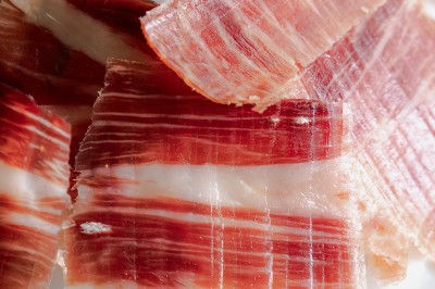 Tentacules de poulpe en train de cuire dans une poêle, manipulés avec une pince en métal.