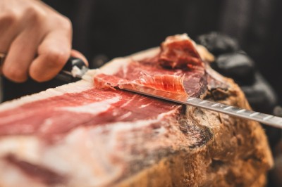 Tentacules de poulpe en train de cuire dans une poêle, manipulés avec une pince en métal.