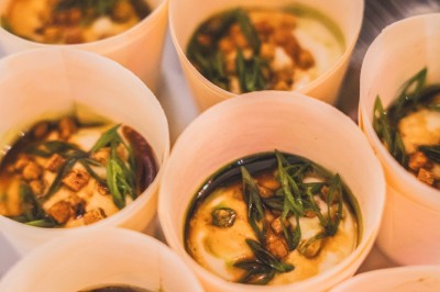 Tentacules de poulpe en train de cuire dans une poêle, manipulés avec une pince en métal.