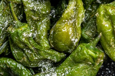 Tentacules de poulpe grillés dans une poêle chaude, manipulés avec une pince en cuisine.