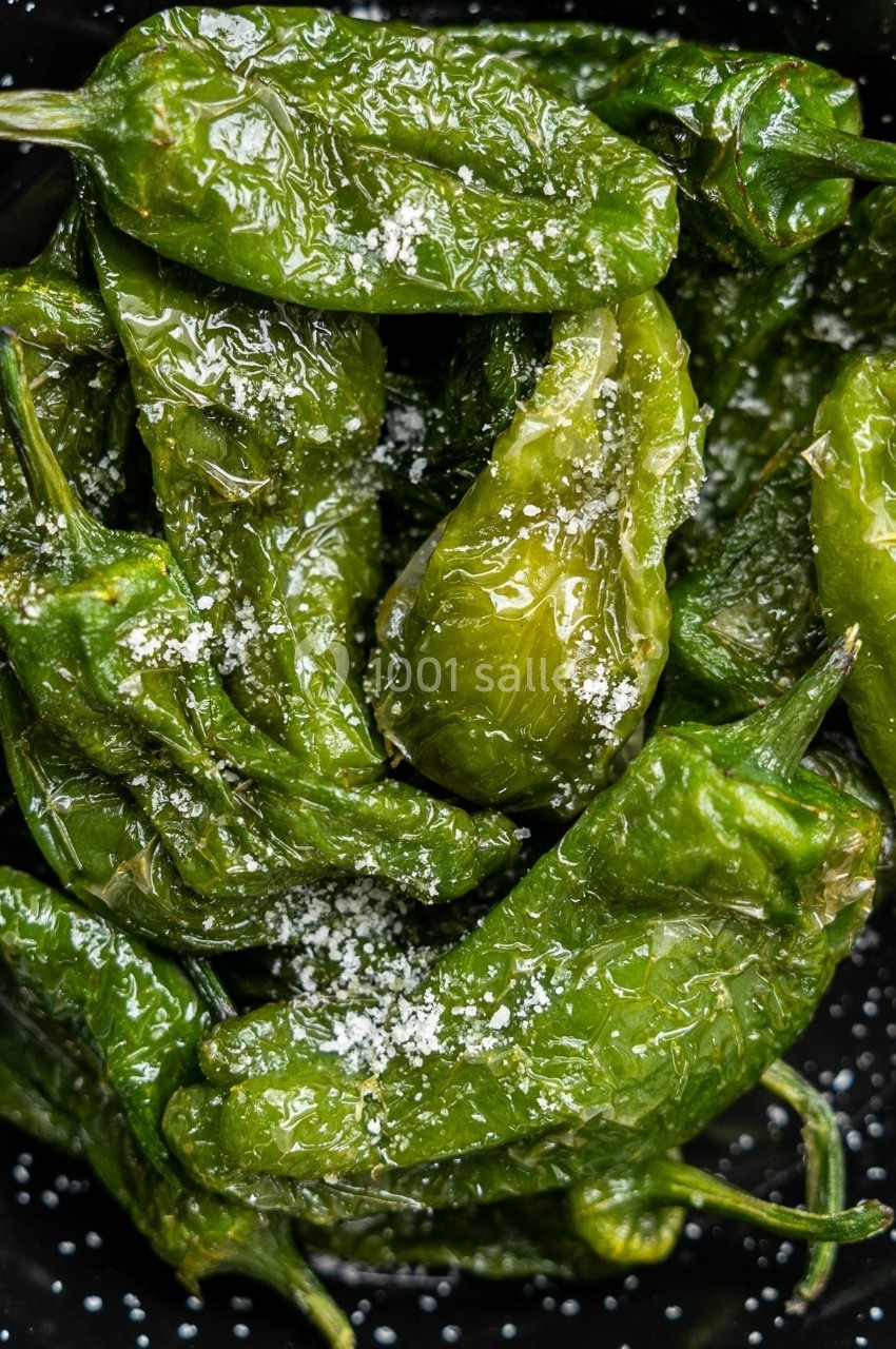 Poêlée de piments verts Padron saupoudrés de sel, présentés dans un bol noir.