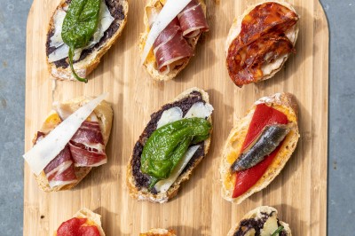 Tentacules de poulpe grillés dans une poêle chaude, manipulés avec une pince en cuisine.