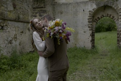 Bouquet de fleurs colorées, sandales vertes, lime coupée, bougie et carton imprimé sur une table en bois.