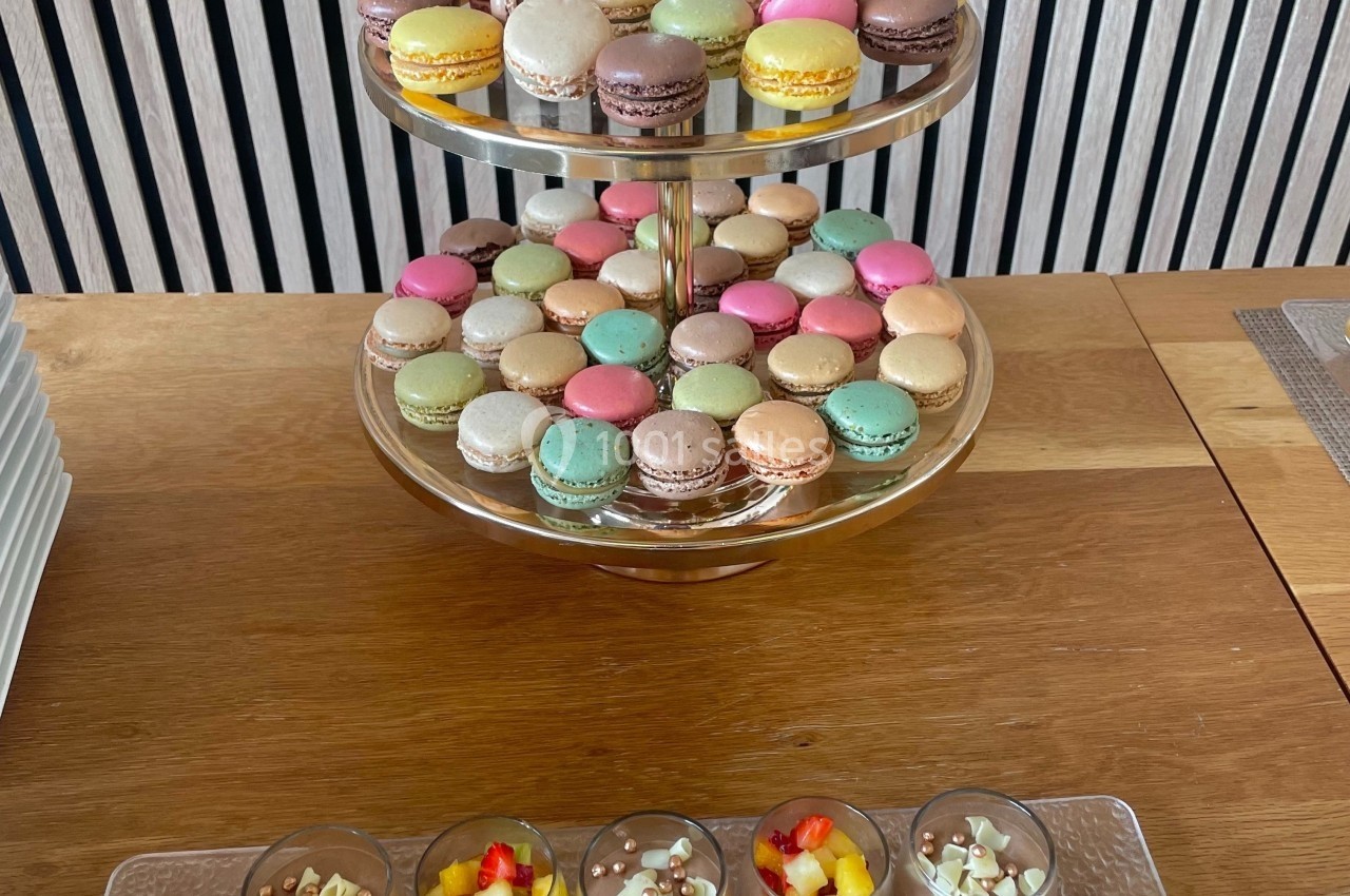 Plateau à deux étages de macarons colorés et verrines de mousse au chocolat garnies de fruits et éclats de chocolat.