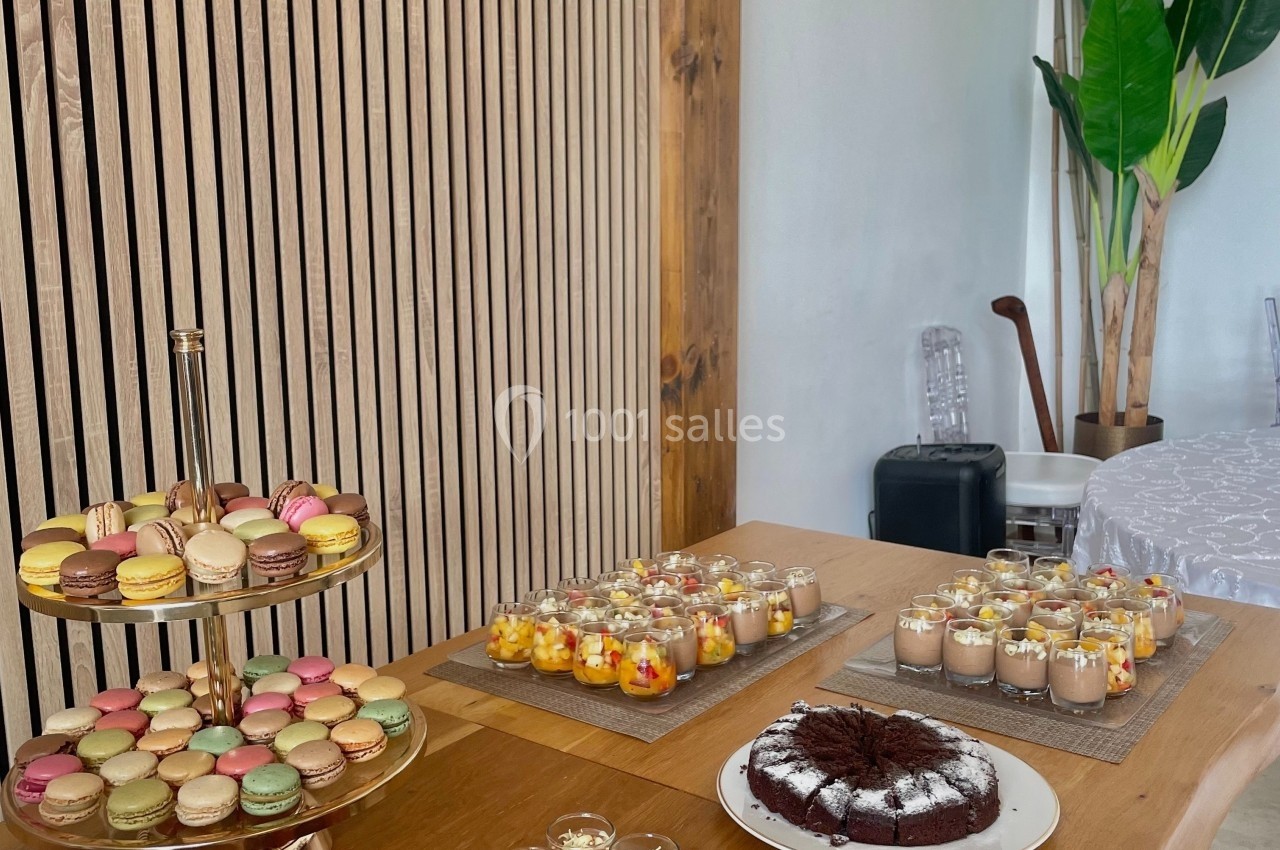 Table en bois garnie de desserts variés, incluant macarons, verrines colorées et gâteau au chocolat.
