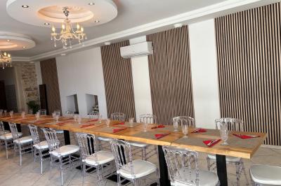 Château entouré de verdure avec ciel bleu, arbres et collines en arrière-plan.