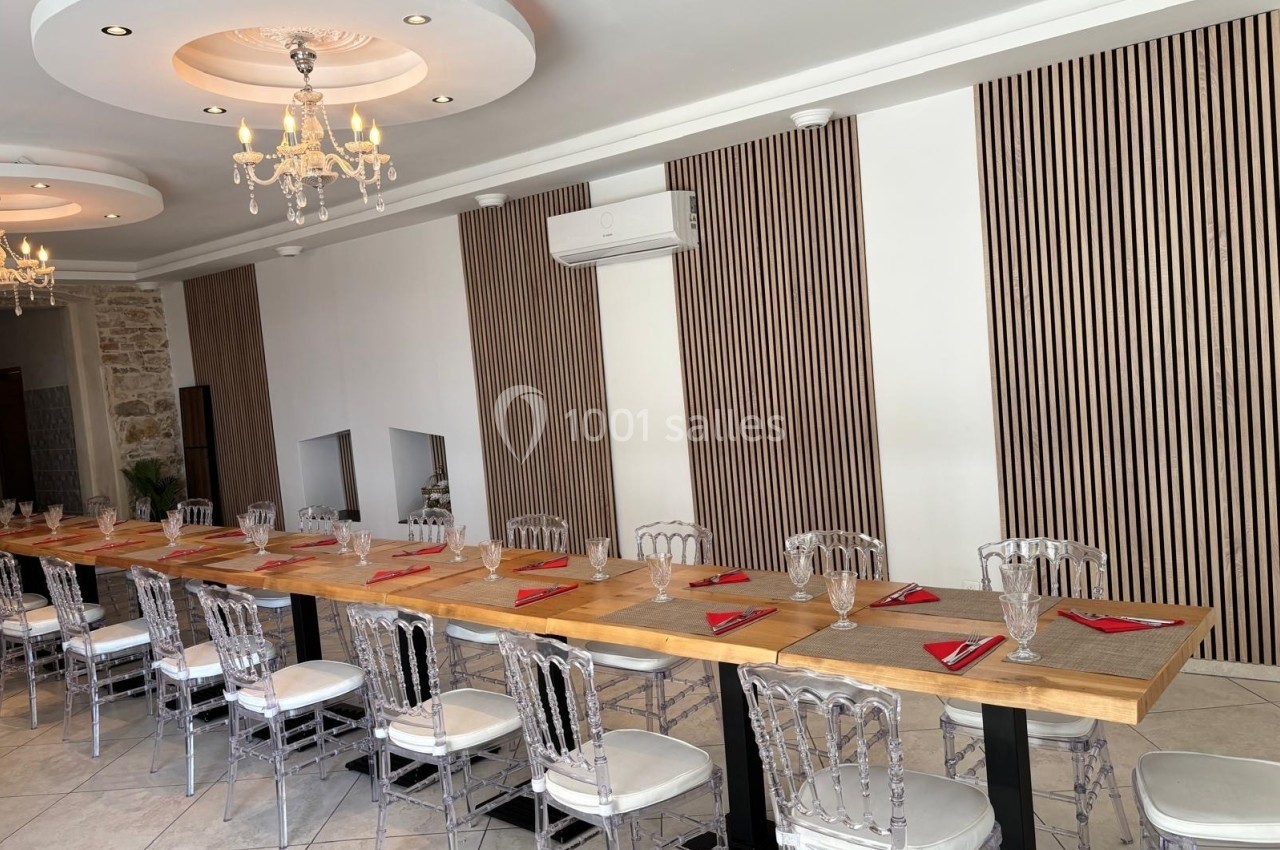 Salle de restaurant lumineuse avec longues tables en bois, chaises transparentes et décoration moderne.