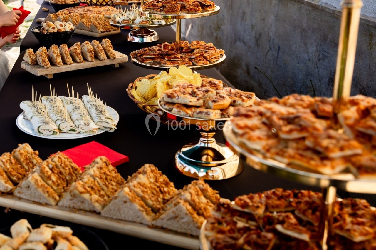 Buffet en extérieur avec une variété de plats salés présentés sur des plateaux dorés et une table noire.