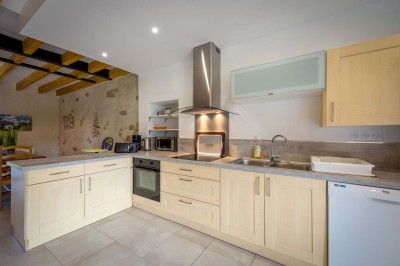 Chambre avec lit double, poutres apparentes, éclairage doux, murs décorés et mobilier blanc.