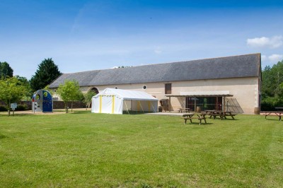 Chambre avec lit double, poutres apparentes, éclairage doux, murs décorés et mobilier blanc.