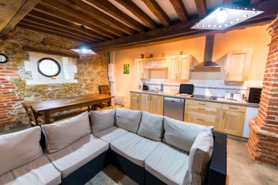 Chambre avec lit double, poutres apparentes, éclairage doux, murs décorés et mobilier blanc.