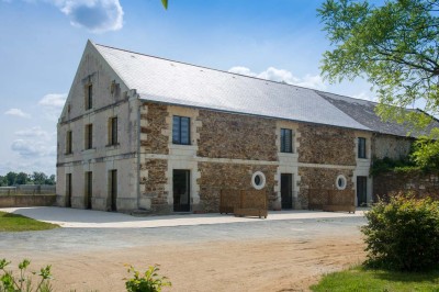 Chambre avec lit double, poutres apparentes, éclairage doux, murs décorés et mobilier blanc.
