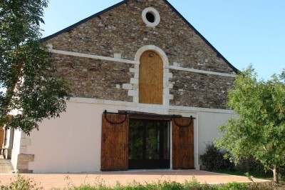 Chambre avec lit double, poutres apparentes, éclairage doux, murs décorés et mobilier blanc.