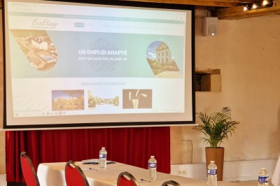 Chambre avec lit double, poutres apparentes, éclairage doux, murs décorés et mobilier blanc.