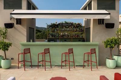 Table rouge avec assiettes, pain, olives, tomates, houmous, boisson orange et lampe, en extérieur.