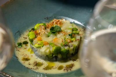 Table rouge avec assiettes, pain, olives, tomates, houmous, boisson orange et lampe, en extérieur.