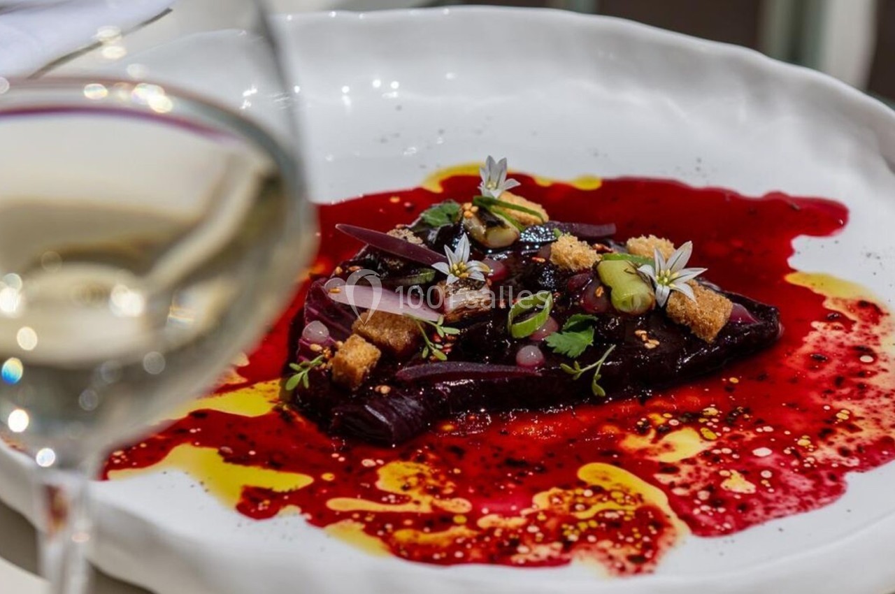 Assiette gastronomique avec betteraves, fleurs comestibles et croûtons, accompagnée d'un verre de vin blanc flou au premier…