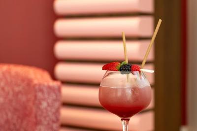 Table rouge avec assiettes, pain, olives, tomates, houmous, boisson orange et lampe, en extérieur.