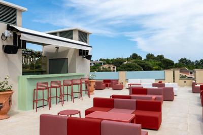 Table rouge avec assiettes, pain, olives, tomates, houmous, boisson orange et lampe, en extérieur.