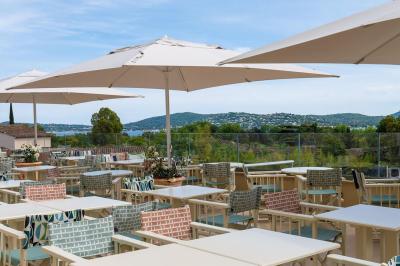 Table rouge avec assiettes, pain, olives, tomates, houmous, boisson orange et lampe, en extérieur.
