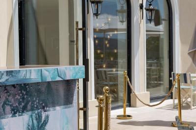 Table rouge avec assiettes, pain, olives, tomates, houmous, boisson orange et lampe, en extérieur.