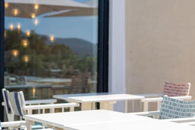 Table rouge avec assiettes, pain, olives, tomates, houmous, boisson orange et lampe, en extérieur.