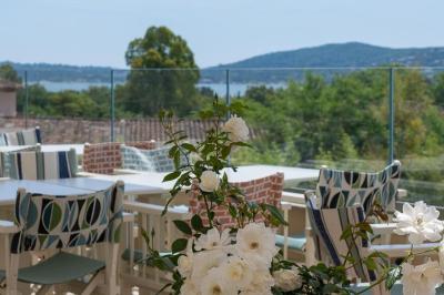 Table rouge avec assiettes, pain, olives, tomates, houmous, boisson orange et lampe, en extérieur.