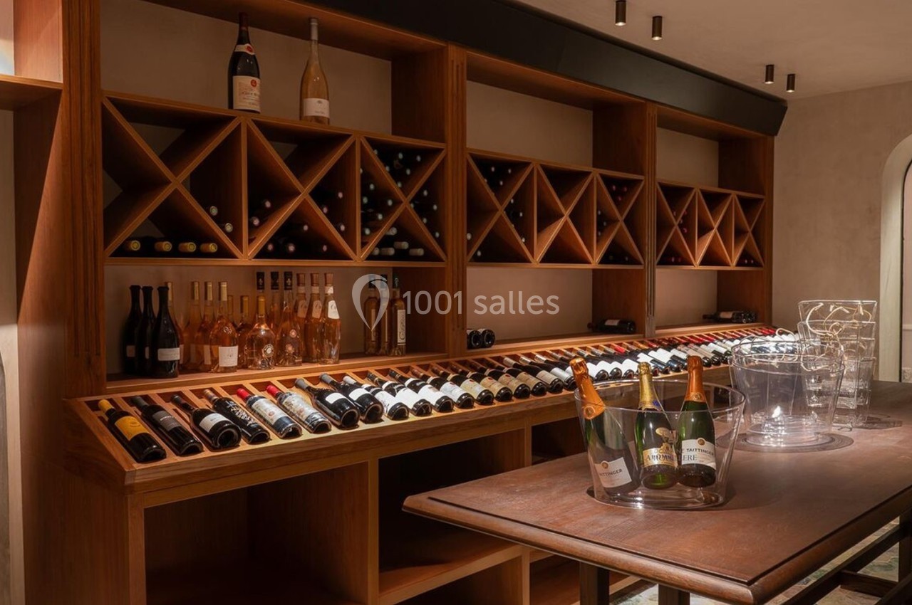 Cave à vin aménagée avec étagères en bois, bouteilles de vin et table en bois avec seaux à champagne.