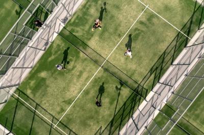Salle à manger élégante avec table dressée, chaises rouges, murs dorés, lustres et grandes fenêtres avec rideaux jaunes.