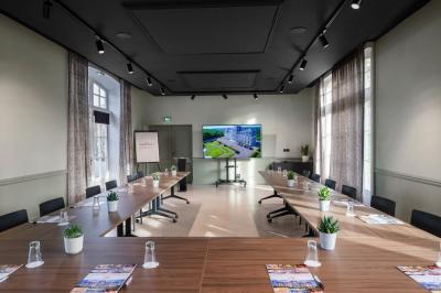 Salle à manger élégante avec table dressée, chaises rouges, murs dorés, lustres et grandes fenêtres avec rideaux jaunes.