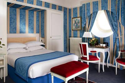 Salle à manger élégante avec table dressée, chaises rouges, murs dorés, lustres et grandes fenêtres avec rideaux jaunes.