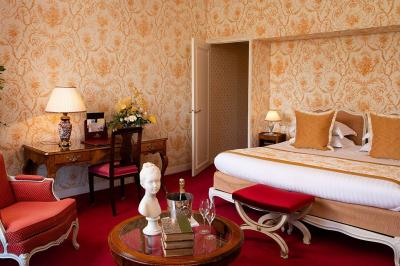 Salle à manger élégante avec table dressée, chaises rouges, murs dorés, lustres et grandes fenêtres avec rideaux jaunes.