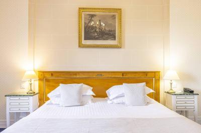 Salle à manger élégante avec table dressée, chaises rouges, murs dorés, lustres et grandes fenêtres avec rideaux jaunes.