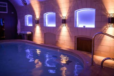 Salle à manger élégante avec table dressée, chaises rouges, murs dorés, lustres et grandes fenêtres avec rideaux jaunes.
