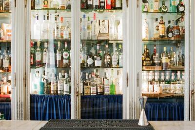 Salle à manger élégante avec table dressée, chaises rouges, murs dorés, lustres et grandes fenêtres avec rideaux jaunes.