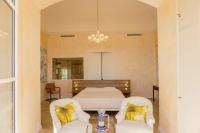 Vue d'une maison en pierre avec piscine, entourée de végétation, donnant sur une vallée et des collines sous un ciel bleu.