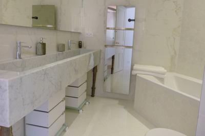 Vue d'une maison en pierre avec piscine, entourée de végétation, donnant sur une vallée et des collines sous un ciel bleu.