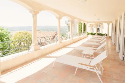 Vue d'une maison en pierre avec piscine, entourée de végétation, donnant sur une vallée et des collines sous un ciel bleu.