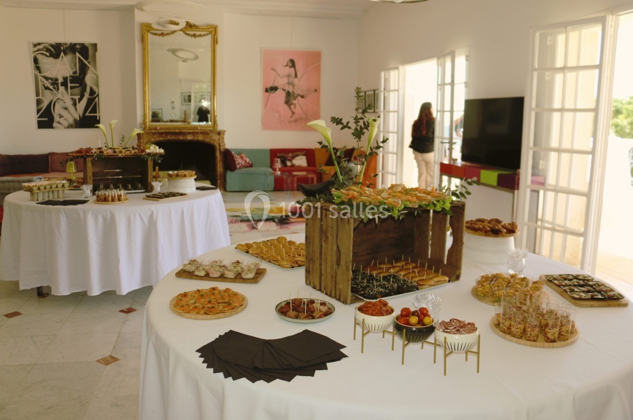 Buffet disposé sur des tables rondes dans une pièce lumineuse avec des décorations murales et un grand miroir.